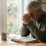 A Christian praying beside an open Bible while seeking guidance about praying for enemies.